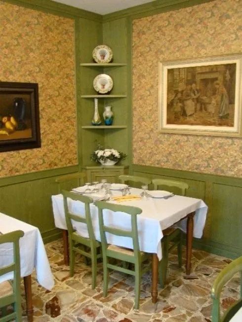 La saletta verde, con boiserie, carta da parati a fiori e tavoli apparecchiati
