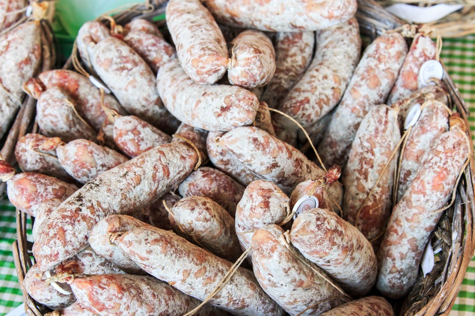 Salami stagionati in un cesto, su una tovaglia a quadretti verdi